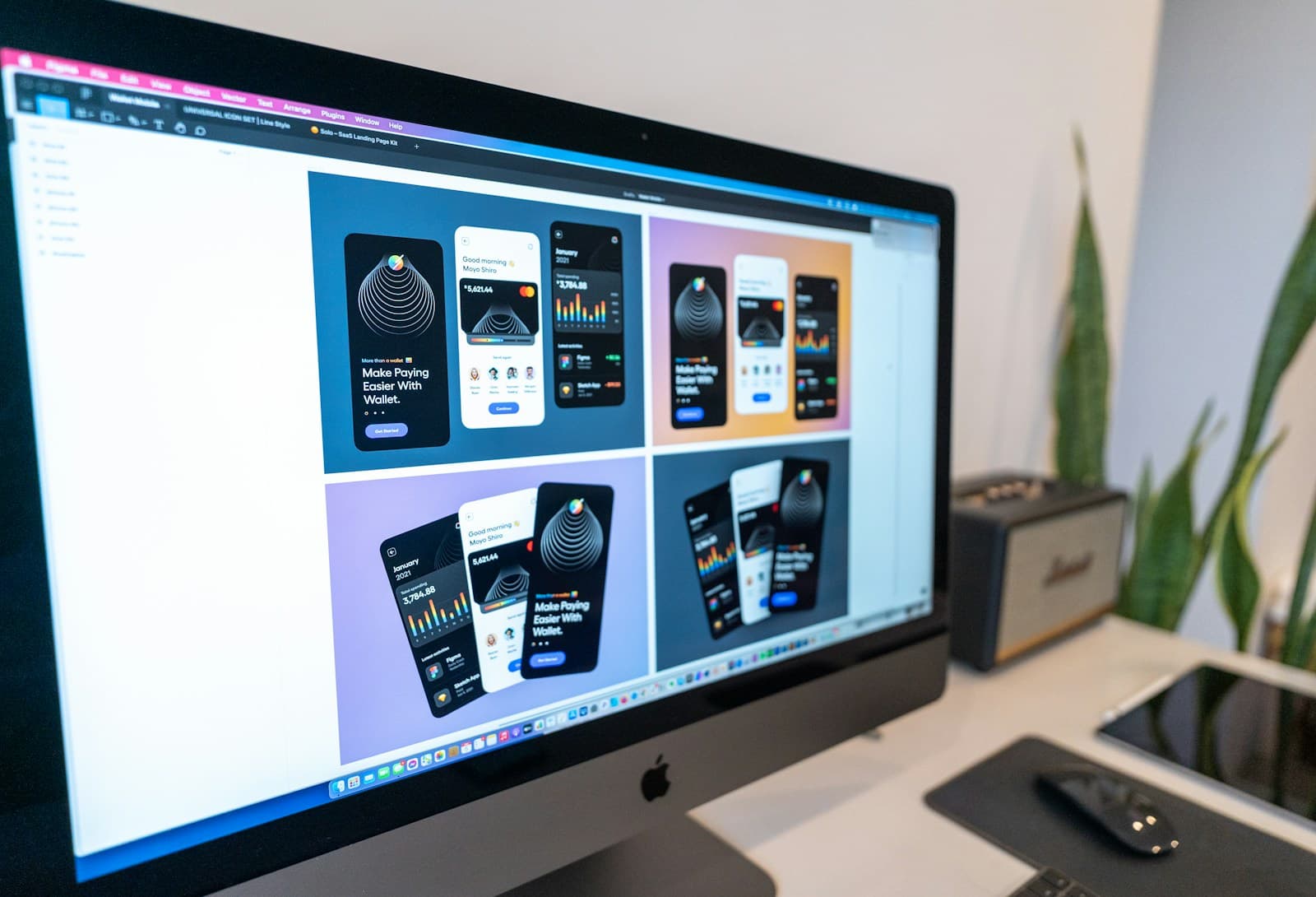 Mobile app screen designs displayed on a large desktop monitor