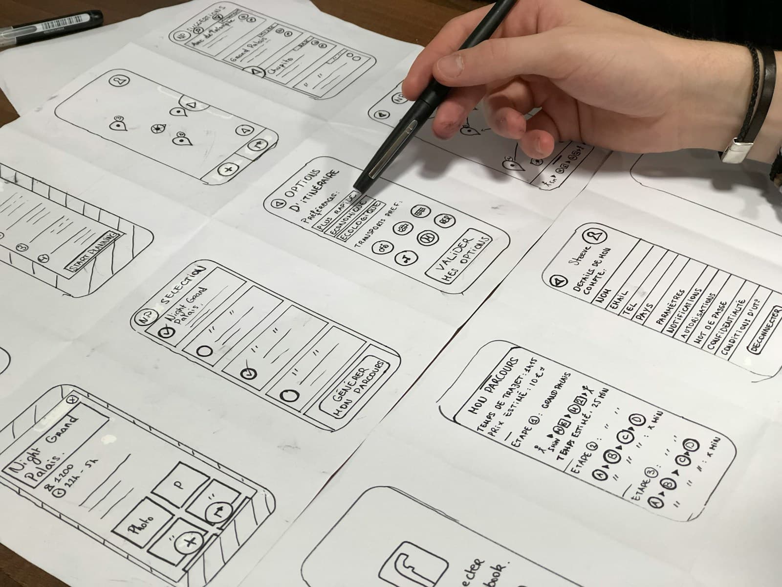 A designer sketching app wireframes with a pen on paper