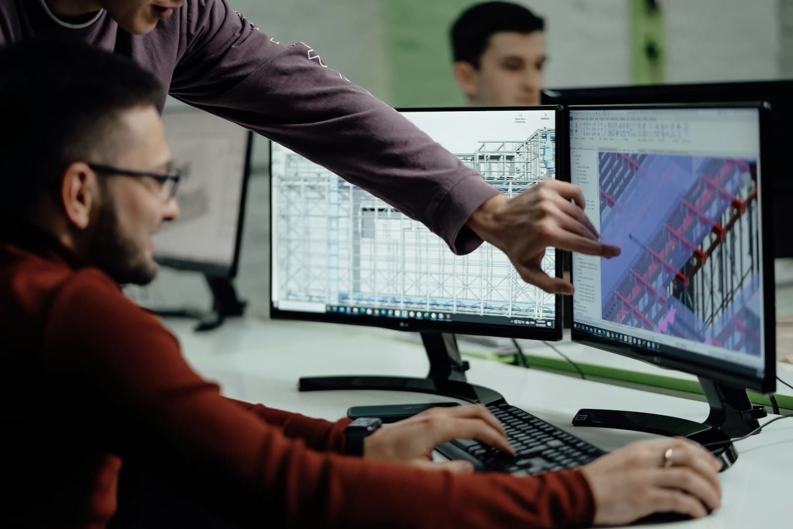 Two engineers reviewing technical designs on a computer screen