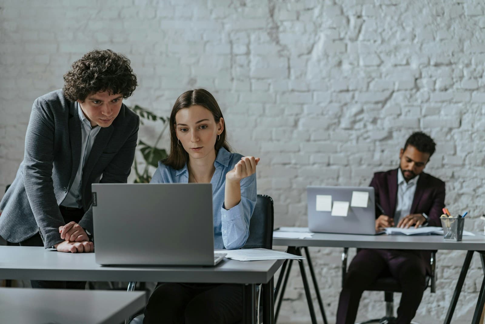 Three colleagues working together at laptops in a bright office