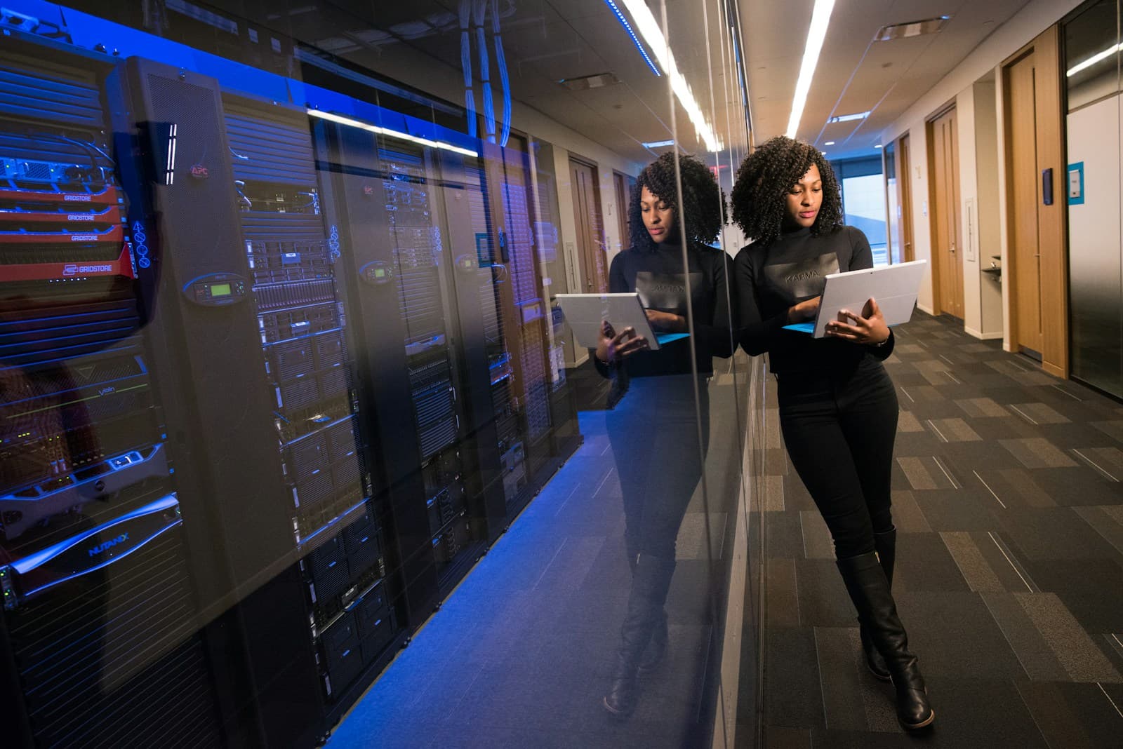 Two engineers with laptops in a data centre aisle between server racks