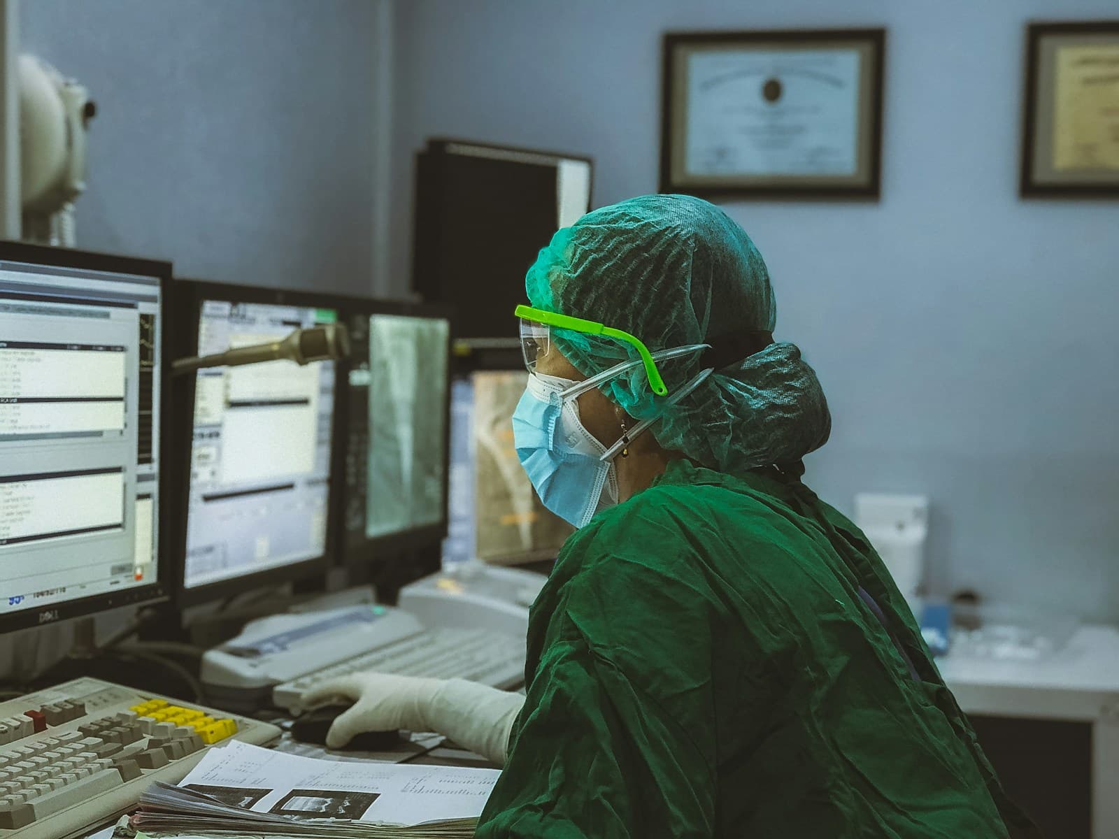 A clinician in scrubs working at several monitors