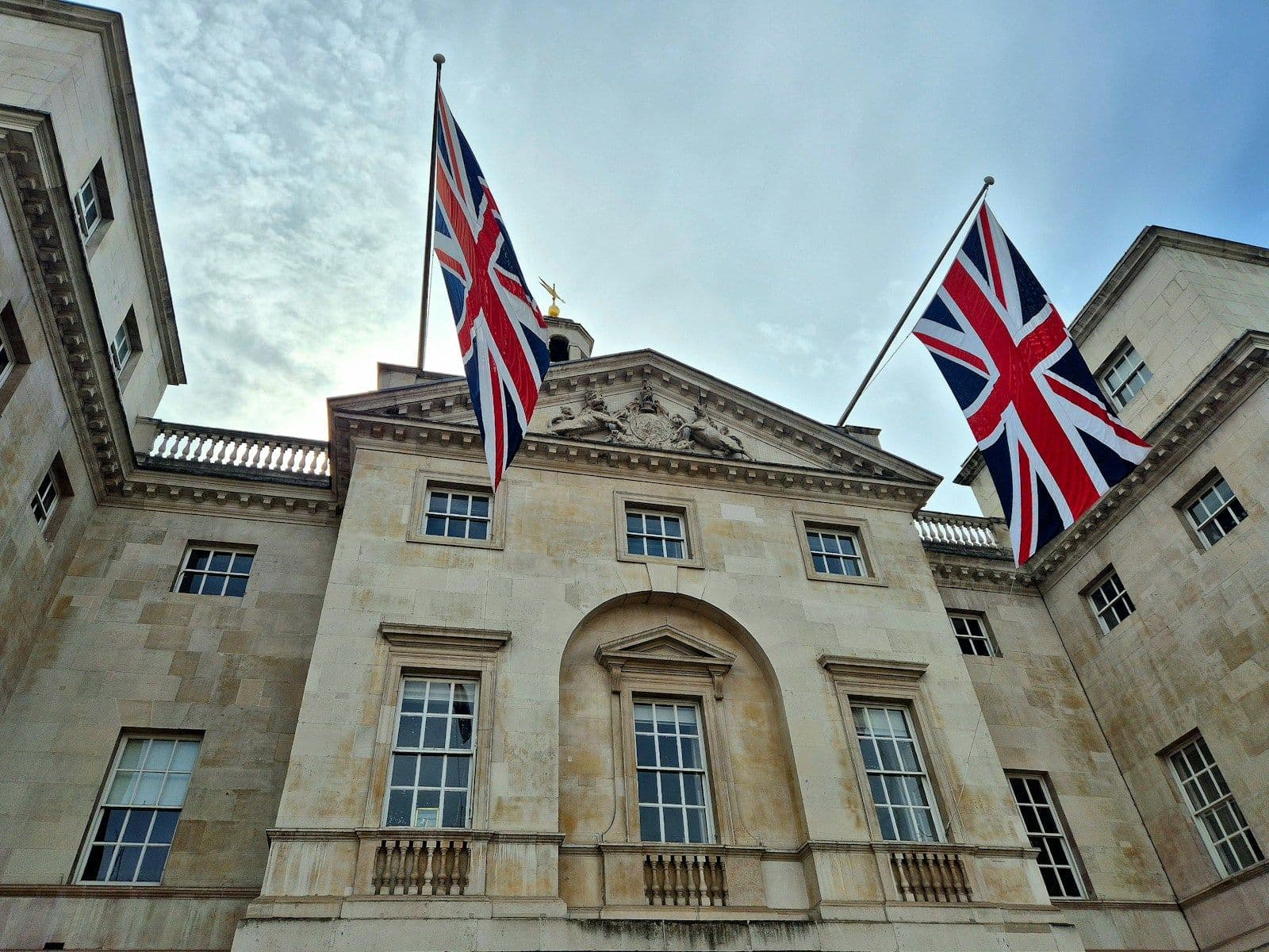 Two Union flags flying from a classical stone government building