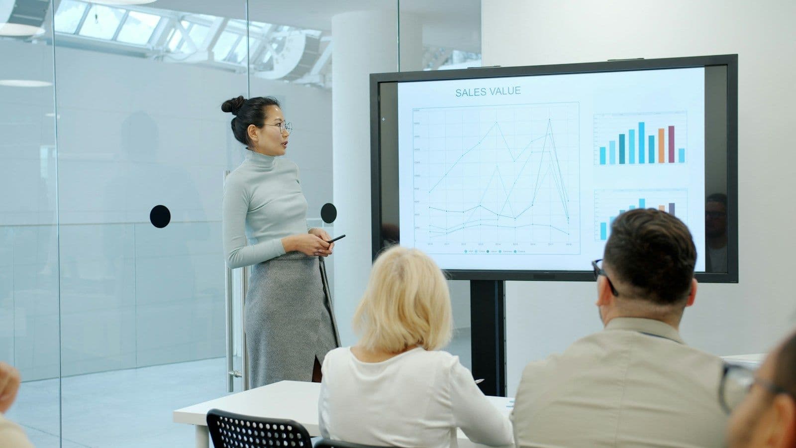 A presenter showing charts on a large screen to colleagues in a meeting room