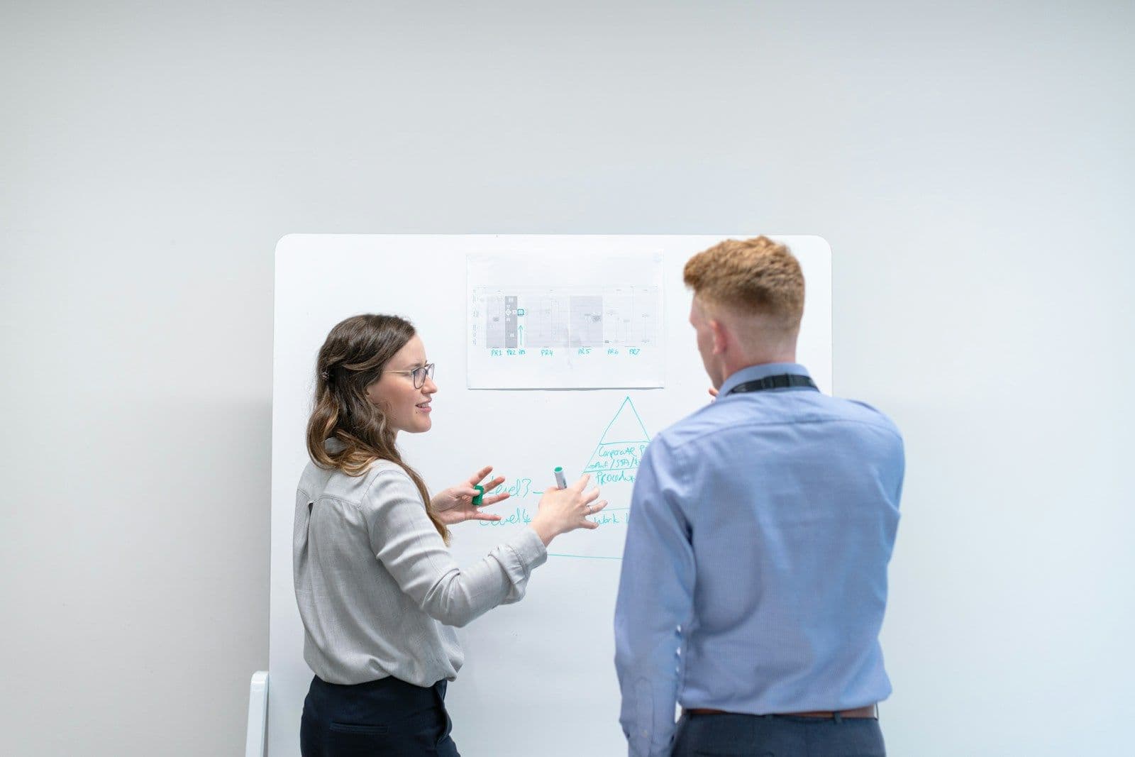 Two colleagues discussing plans at a whiteboard