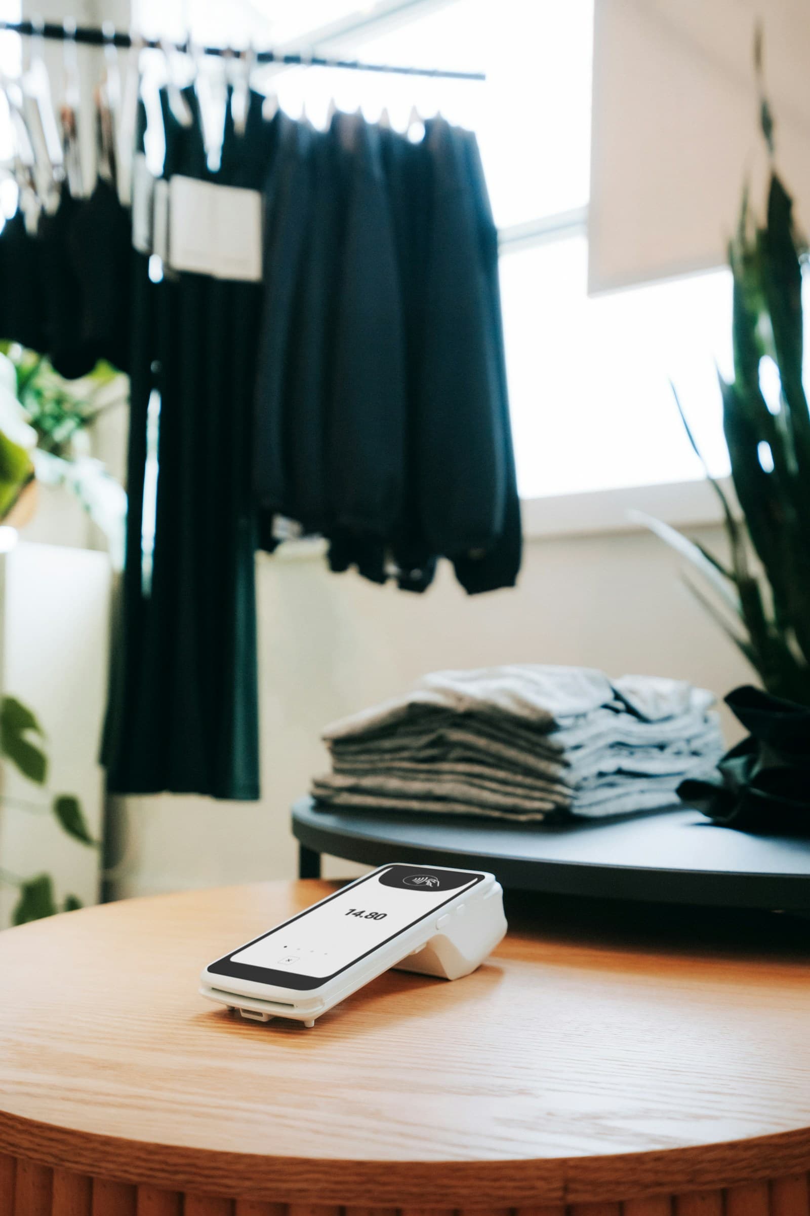 A card payment terminal on a shop counter beside folded clothing