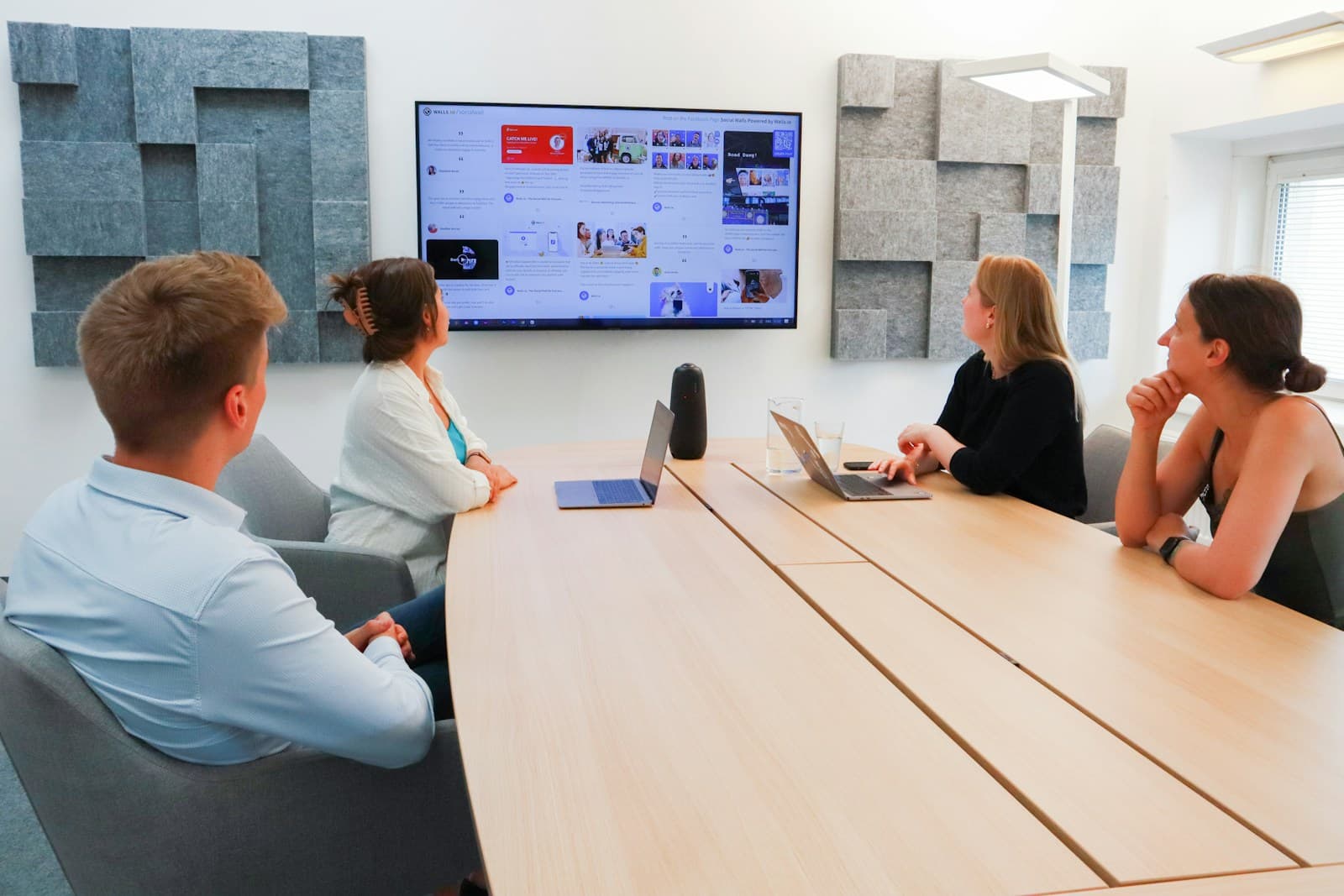 A team in a meeting room with a large screen on the wall