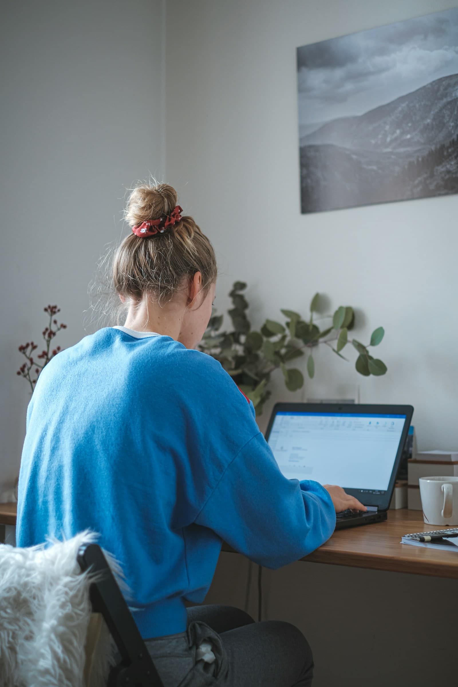 A woman working on a laptop at a desk at home